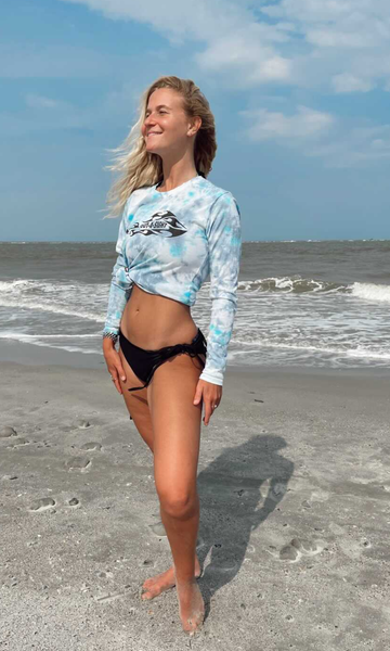 Lady wearing a fishing shirt on a beach.